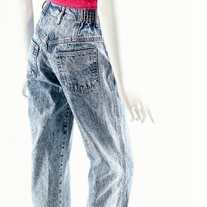 May include: A mannequin wearing a pink fuzzy tank top and light blue acid wash jeans.