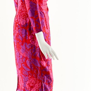 May include: A pink and purple floral print dress with long sleeves. The dress is fitted and has a slight A-line shape.