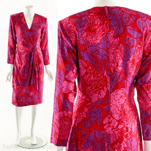 May include: A long-sleeved dress with a V-neckline and a wrap-style bodice. The dress is made of a red and purple floral print fabric.