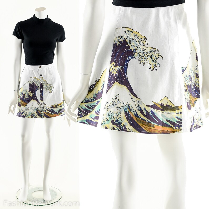 May include: A white skirt with a print of The Great Wave off Kanagawa by Katsushika Hokusai. The skirt is a-line and has a button closure at the front.
