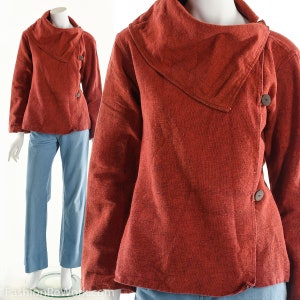May include: A rust-colored, long-sleeved jacket with a large, folded collar. The jacket has a button closure and is made of a soft, textured fabric.