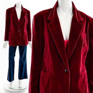 May include: A burgundy velvet blazer with a single-button closure and notched lapels. The blazer is paired with blue denim pants. The jacket has two front pockets and is displayed on a mannequin.