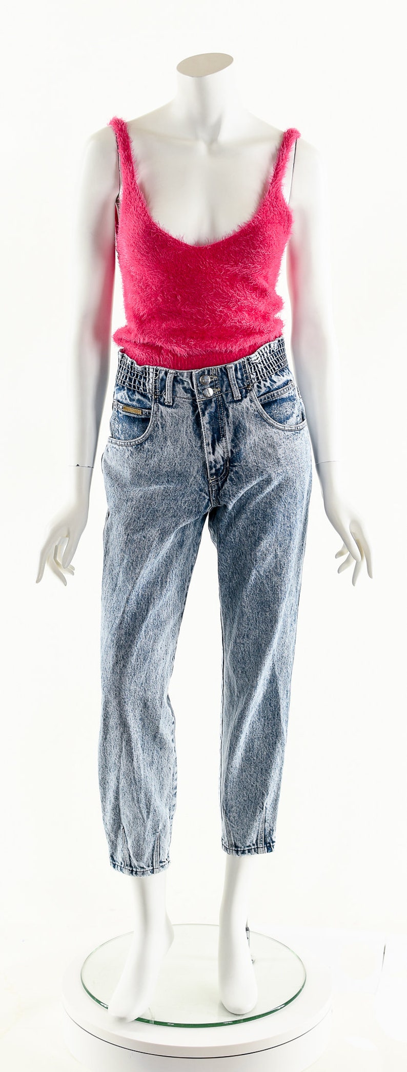 May include: A pink fuzzy tank top with a pair of light blue denim jeans with a high waist.