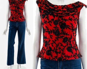 May include: A red sleeveless top with a black floral pattern. The top has a cowl neck and a fitted bodice.