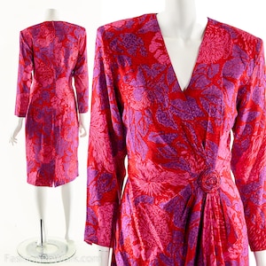 May include: A long-sleeved wrap dress with a V-neckline. The dress is made of a silky fabric and features a vibrant floral print in shades of pink and purple.