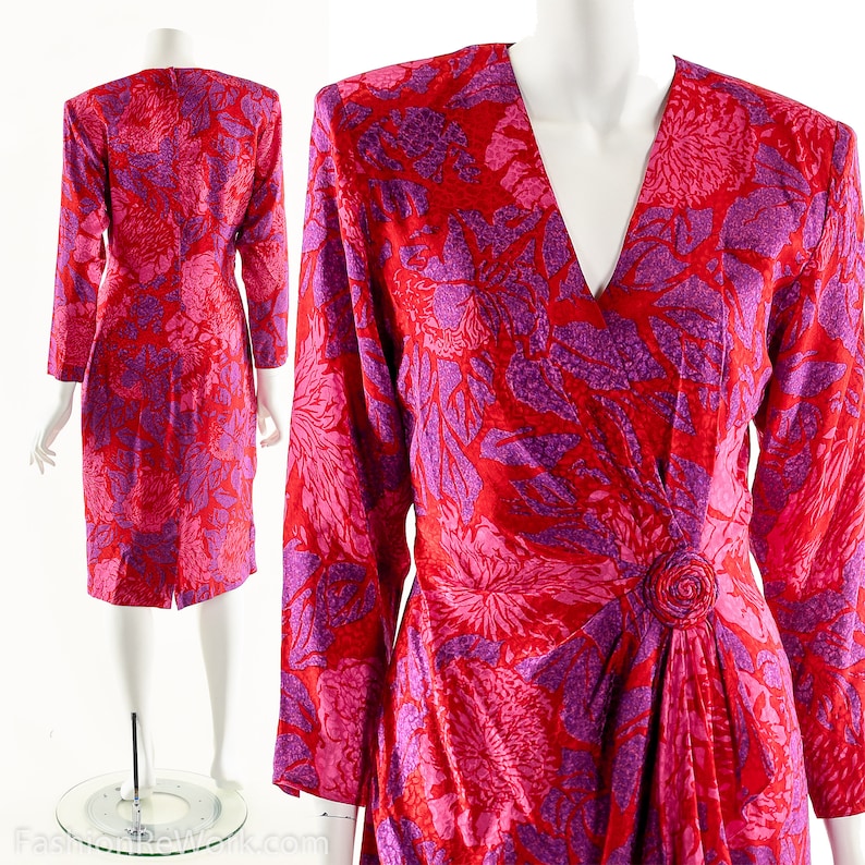 May include: A long-sleeved wrap dress with a V-neckline. The dress is made of a silky fabric and features a vibrant floral print in shades of pink and purple.