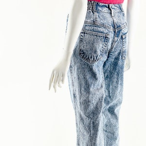 May include: A mannequin wearing a pink fuzzy crop top and light blue acid wash denim jeans.