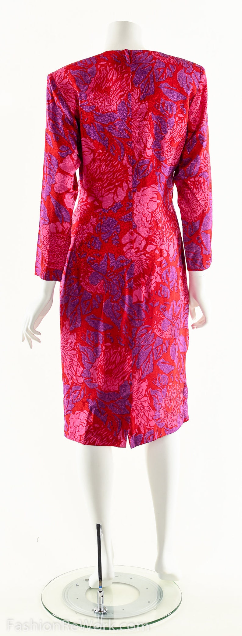 May include: A red and purple floral print dress with long sleeves. The dress has a fitted silhouette and a slightly flared skirt.