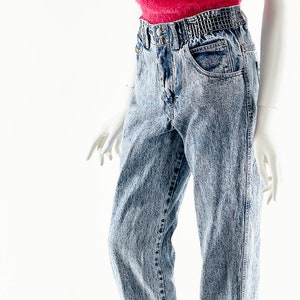 May include: A mannequin wearing a pink fuzzy tank top and light blue denim jeans with a high waist and a relaxed fit.