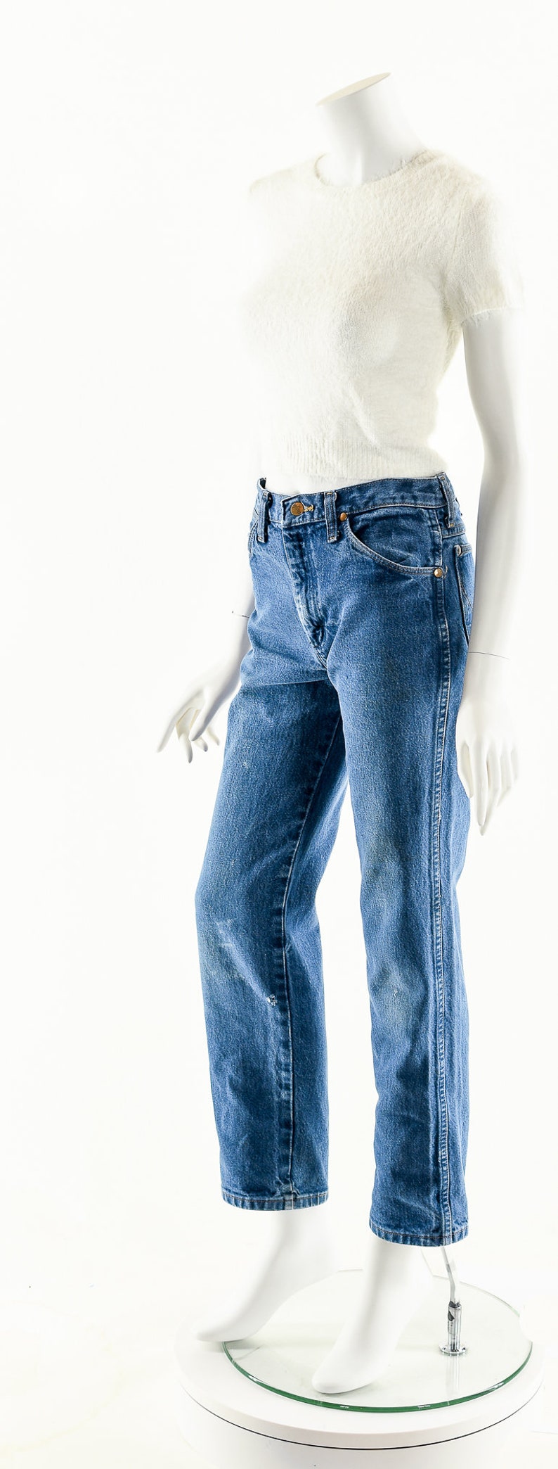 Puede incluir: Un par de pantalones vaqueros azules de mezclilla con cintura alta y piernas rectas. Los pantalones vaqueros est&aacute;n en un maniqu&iacute; blanco.