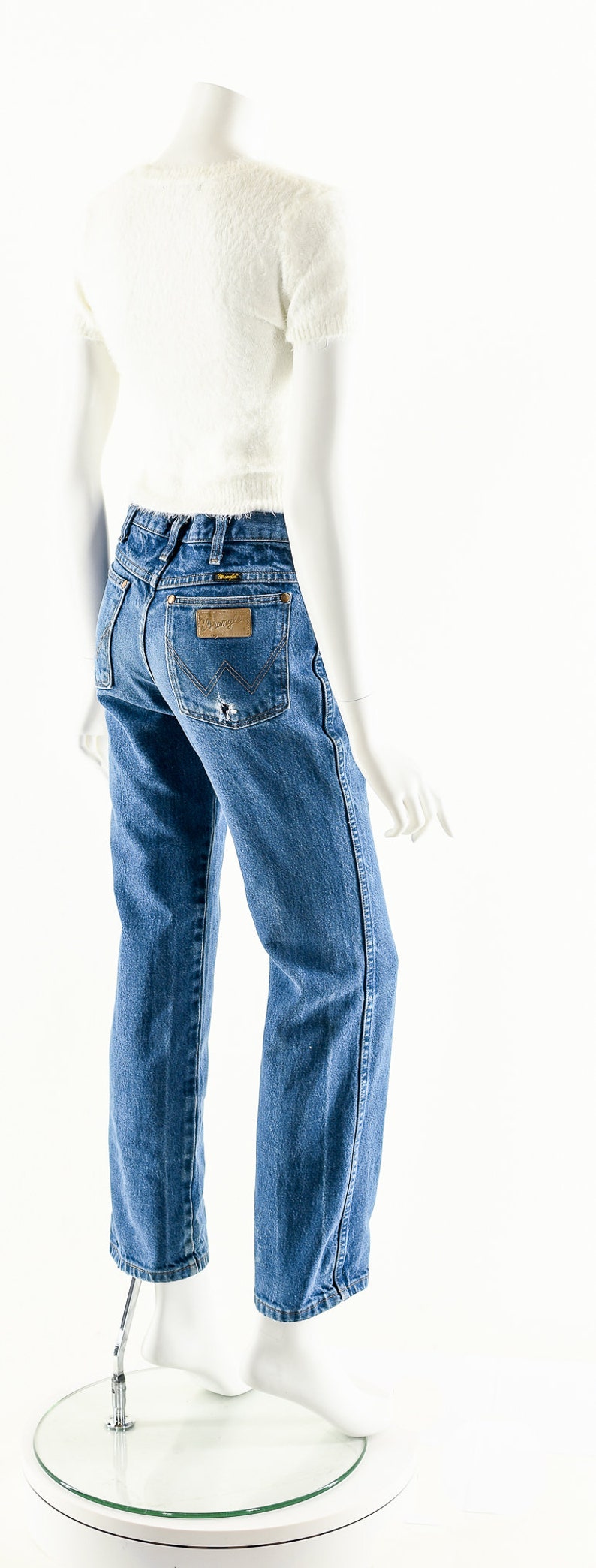 Puede incluir: Un par de pantalones vaqueros azules con un parche de cuero marr&oacute;n en el bolsillo trasero que dice "Wrangler".