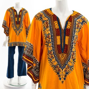 Puede incluir: Una camisa amarilla de manga larga con cuello en V y un patrón geométrico en tonos azules, rojos y marrones. La camisa tiene un corte holgado y una silueta fluida.