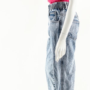 May include: A mannequin wearing a pink fuzzy tank top and light blue acid wash jeans with a wide elastic waistband.