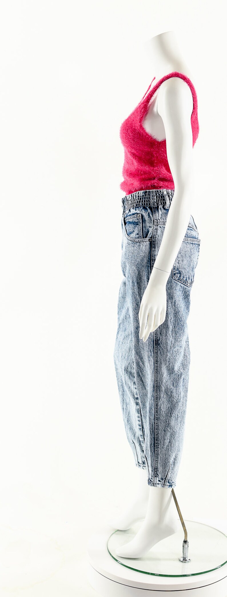 May include: A mannequin wearing a pink fuzzy tank top and light blue acid wash jeans with a wide elastic waistband.