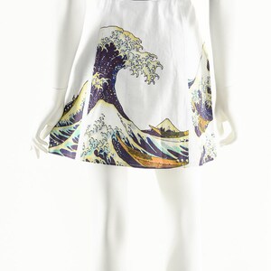 May include: A white skirt with a printed image of a large wave, inspired by the famous Japanese woodblock print "The Great Wave off Kanagawa". The skirt is paired with a black short-sleeved shirt.