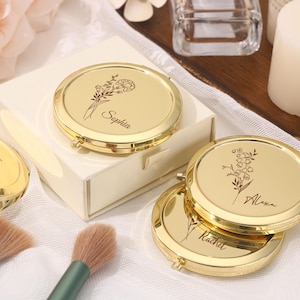 May include: Gold compact mirrors with floral engravings and personalized names. The mirrors are displayed with makeup brushes and a gift box. The names "Sophia", "Alexa", and "Rachel" are visible on the compacts.