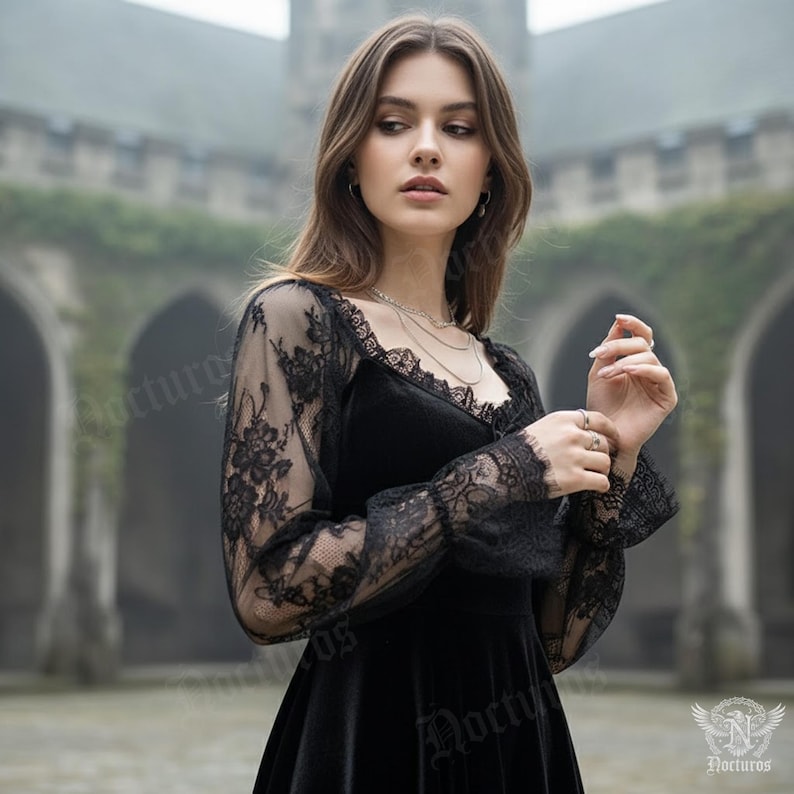 May include: Black velvet dress with lace sleeves. The dress features a square neckline and delicate lace detailing on the sleeves and cuffs. The sleeves are sheer, revealing the arms beneath. The dress is a gothic style.