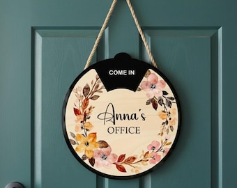 May include: Round wooden office sign with a black border and a rope for hanging. The sign features the text "Come In" at the top and "Anna's OFFICE" in elegant script, surrounded by a floral design in shades of pink, orange, and brown.