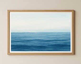 May include: A framed print depicting a serene ocean scene. The artwork features shades of blue, with the water in the foreground and a lighter sky above. The print is encased in a natural wood frame, adding a touch of warmth to the cool tones.