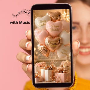 Può includere: Uno schermo di smartphone che mostra un'immagine digitale di un gruppo di palloncini a forma di cuore nei toni dell'oro rosa, crema e bianco, ciascuno stampato con il testo Happy Birthday, che fluttuano sopra diversi pacchetti regalo.