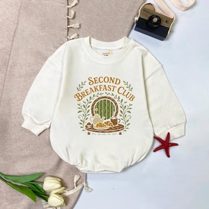 May include: A white ceramic mug with a black handle and the text "But First, Coffee" in a bold, black font. The mug is set against a blurred background, suggesting a cozy setting.