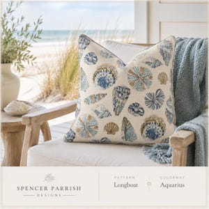 May include: A square throw pillow featuring a cream-colored fabric base with a repeating pattern of various seashells in shades of blue, tan, and brown. The text on the image reads Spencer Parrish Designs, Pattern Longboat, Colorway Aquarius.