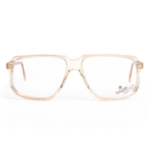 May include: A pair of clear, rectangular spectacles with a brown frame. The frame has the word "Indigiline" printed on the right side.