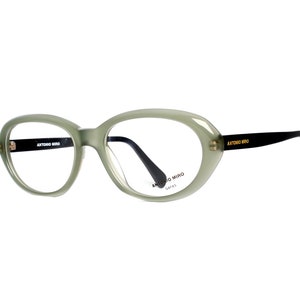 May include: Green oval-shaped eyeglasses with black arms and the text "ANTONIO MIRO" on the arms and the lens.