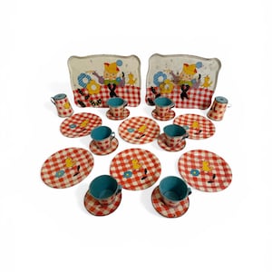 May include: A vintage children's tea set with a red and white checkered pattern. The set includes plates, saucers, cups, and small pitchers. Each piece features a cartoon illustration of a child and a duck. The set is displayed on a white background.