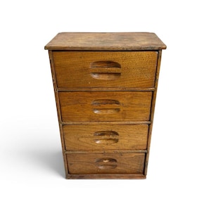 May include: A small wooden chest of drawers featuring four stacked drawers with integrated horizontal recessed handles. The unit is constructed from medium-brown wood with a visible grain pattern and a flat rectangular top surface.