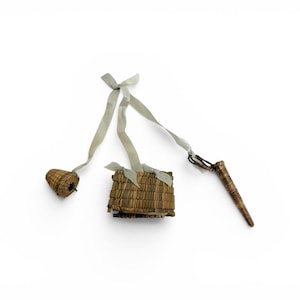 May include: A collection of small, woven items, including a basket-shaped object, a small square pouch, and a pointed tool. All items are made of natural-colored woven material and are connected by light gray ribbons.
