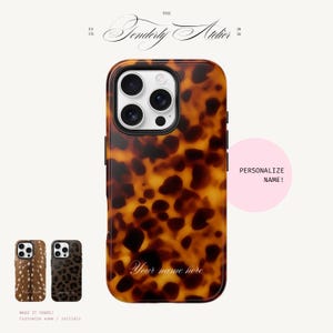 May include: A rectangular smartphone case featuring a brown and black tortoiseshell pattern. The case includes a triple camera cutout and the text "Your name here" in a white script font. A pink circle contains the text "PERSONALIZE NAME!".