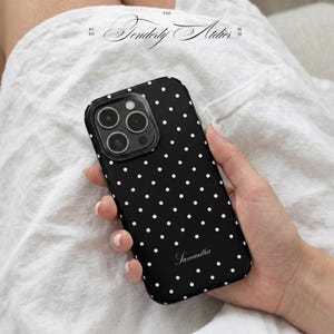 Pode incluir: Capa de telefone preta com bolinhas brancas, segurada em uma mão. A capa tem um recorte para a câmera e o nome "Samantha" em script. A capa está em um fundo branco. O texto "The Tenderly Atelier 2020" está no canto superior esquerdo.