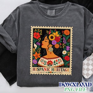 May include: A charcoal gray t-shirt featuring a graphic design shaped like a postage stamp. The illustration depicts a person in profile adorned with a vibrant floral crown and a patterned blouse, with the text HISPANIC HERITAGE at the bottom.