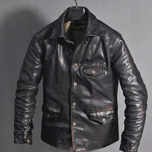 May include: A black leather jacket with a classic design, featuring a collared neckline, button-down front, and multiple pockets. The jacket has a worn, distressed appearance, with visible wear and tear on the leather. The sleeves are long and fitted.