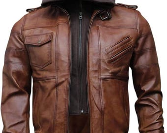 May include: Brown leather jacket with a detachable hood. The jacket features a zip-up front, multiple pockets, and ribbed cuffs and hem. The jacket has a bomber style with a brown hood.