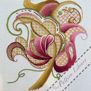 May include: Detailed embroidery of a floral design in pink, green, and gold hues. The design is set against a white backdrop and features intricate stitch work. The text "Pattern Library" is visible in the lower right corner.