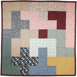 May include: A patchwork quilt with a variety of floral and geometric patterns in shades of pink, blue, green, brown, and yellow. The quilt is made up of squares and rectangles of different sizes and is sewn together with a contrasting thread.