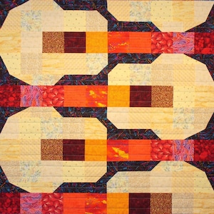 May include: A quilt with a geometric pattern in shades of orange, red, brown, and yellow. The quilt is made up of squares and rectangles, and the pattern is repeated throughout the quilt.