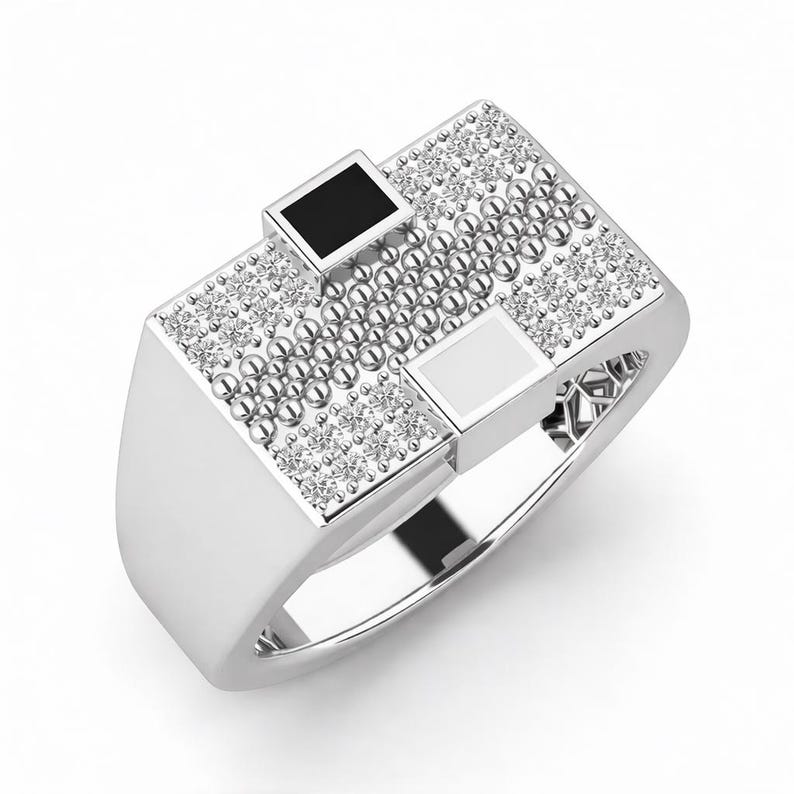 Peut inclure: Une bague en argent avec une face rectangulaire. La face est orn&eacute;e de petites perles rondes argent&eacute;es et de pierres pr&eacute;cieuses rondes et transparentes. Deux incrustations carr&eacute;es, une noire et une blanche, sont serties dans la face.
