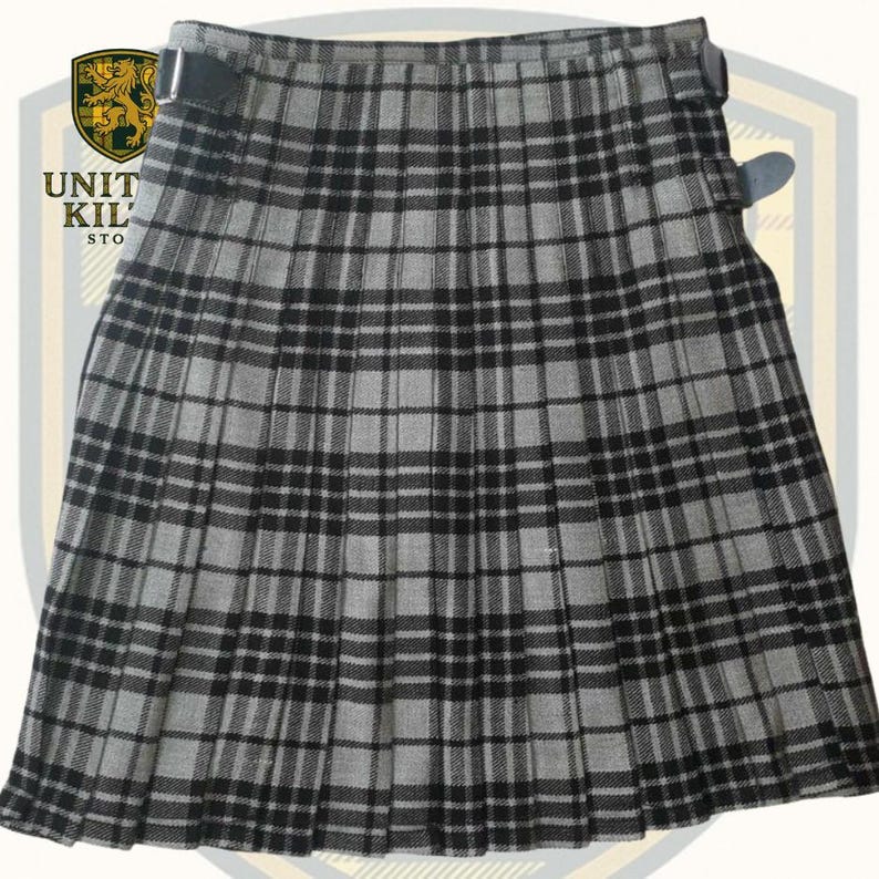 May include: A gray and black plaid kilt with pleats. The kilt has two leather straps with buckles on the side. The kilt is made of a woven fabric. The kilt is a traditional Scottish garment.