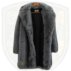 May include: A long, gray faux fur coat with a wide collar, hanging on a wooden hanger. The coat has a black interior and a logo near the bottom. The coat is designed to be worn open.
