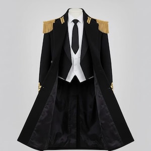 May include: A formal black coat with gold epaulettes and trim, paired with a white vest, black tie, and black trousers. The coat is open, revealing the inner layers of the outfit. The coat has gold fringe on the shoulders.