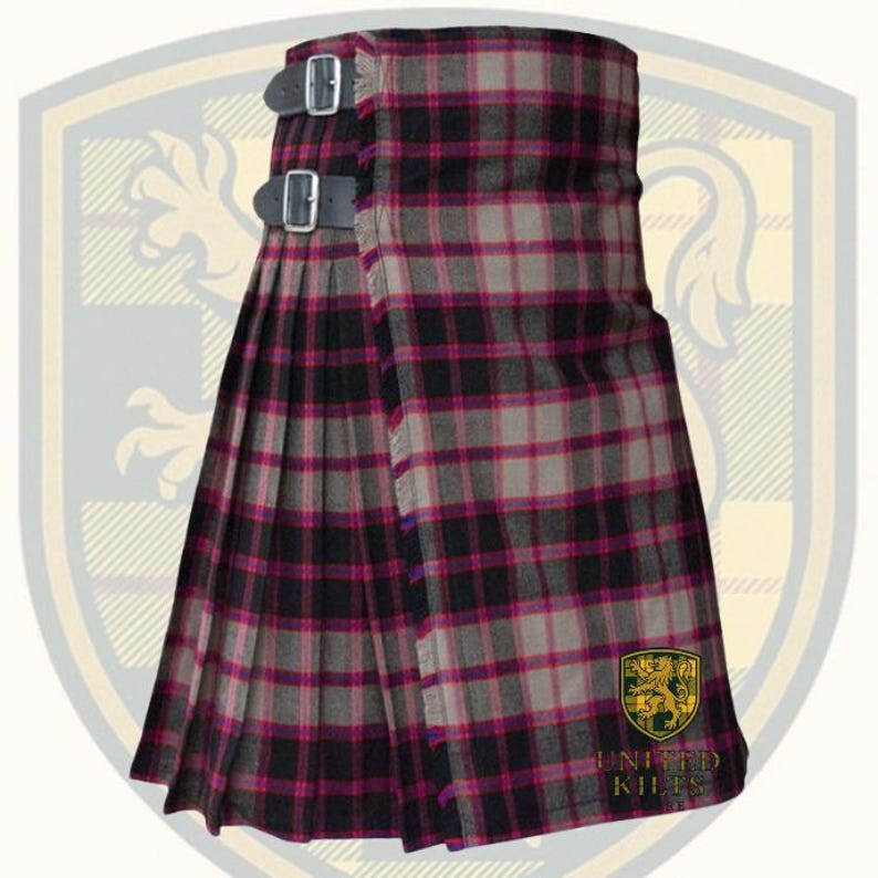 Puede incluir: Un kilt tradicional con un patr&oacute;n de cuadros en tonos negro, gris y magenta. El kilt tiene dos correas de cuero con hebillas plateadas y est&aacute; plisado. En la esquina inferior derecha se muestra un emblema dorado y verde con el texto "UNITED KILTS".