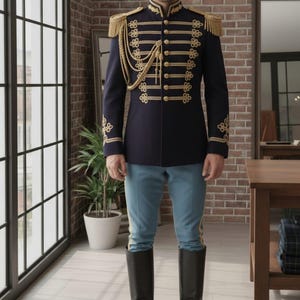 May include: A navy blue military-style jacket with gold trim, epaulets, and decorative buttons. The jacket is paired with light blue pants and black riding boots. The outfit is displayed in a room with a brick wall and large windows.