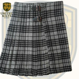 May include: A gray and black plaid kilt with two leather straps and buckles. The kilt is pleated and features the text "UNITED KILTS STORE" and a crest logo.
