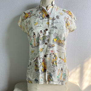 May include: A white short-sleeved shirt with a Hawaiian print featuring hula dancers, tropical fruits, and the text "PAU RIDER", "ALOHA", and "HAWAII".