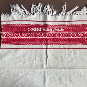 Könnte beinhalten: Ein weißes Baumwoll-Geschirrtuch mit einem roten bestickten Rand. Die Stickerei zeigt ein geometrisches Muster und den Text "KOJDEJEPAJ".