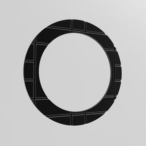 Può includere: Un oggetto circolare nero con un motivo strutturato a griglia. L'oggetto ha un centro cavo, creando una forma ad anello. Il design è semplice e moderno, con un focus su forme geometriche e contrasti di luce e ombra.