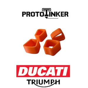 May include: Four orange, square-shaped rubber components. The text "PROTO LINKER" is above the components, and the text "DUCATI TRIUMPH" is below. The components are likely for motorcycle parts.
